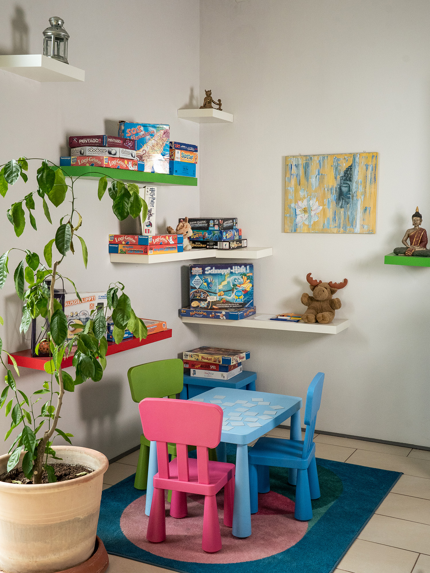 Spielecke mit buntem Kindertisch, Stühlen und Gesellschaftsspielen in der Praxis